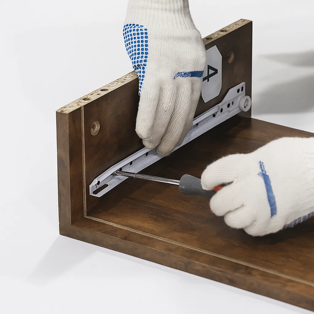 Homme à genoux fixant des traverses métalliques au cadre de la console.