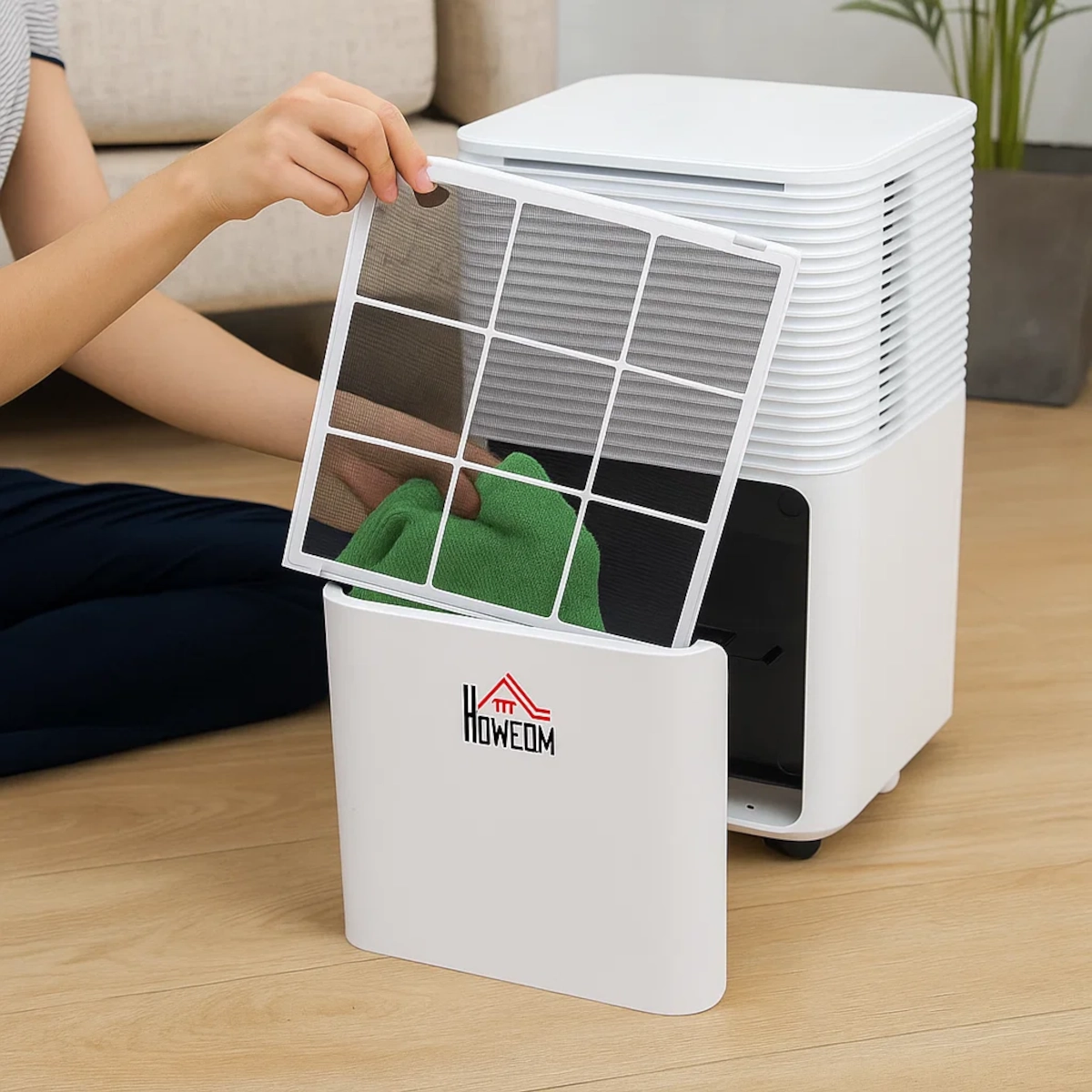 Personne retirant le filtre à mailles d'un déshumidificateur HOMCOM blanc pour le nettoyer à la maison.