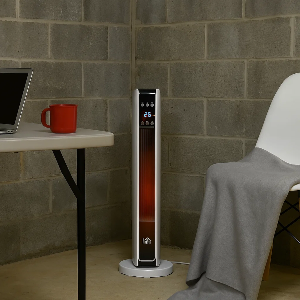 Un chauffage d'appoint chauffe un espace de travail au sous-sol avec une table, un ordinateur portable et un mug rouge.