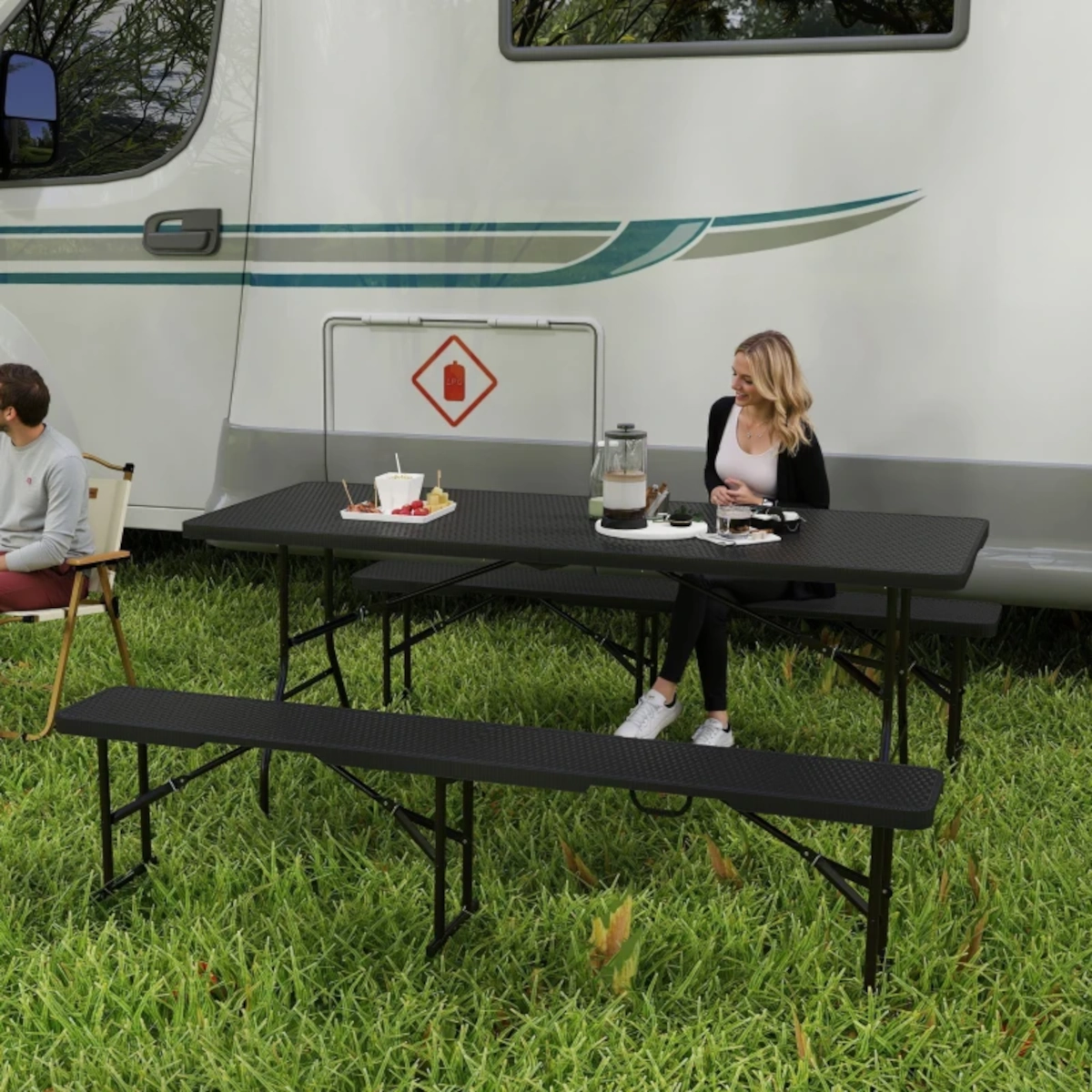 Table de pique-nique pliante en plastique blanche sur une pelouse, parfaite pour des fêtes ou des événements en plein air.