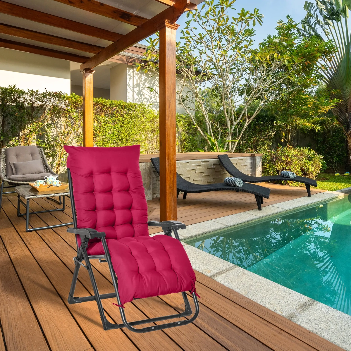 Fauteuil zéro gravité rouge vif rembourré au bord de la piscine sous une pergola en bois avec un paysage tropical.
