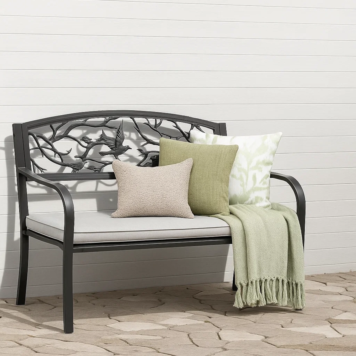 Des coussins colorés et des plaids doux disposés sur un banc de jardin pour plus de confort.