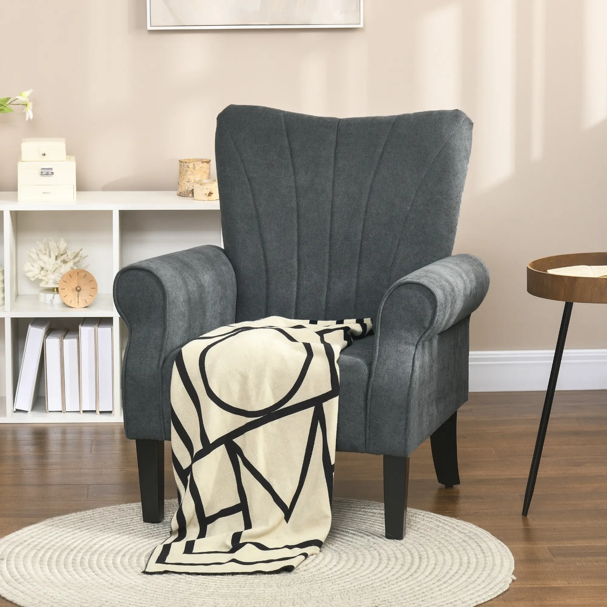Fauteuil d'appoint gris foncé avec des accoudoirs roulés et une couverture à motifs audacieux dans une pièce aux tons neutres confortable.