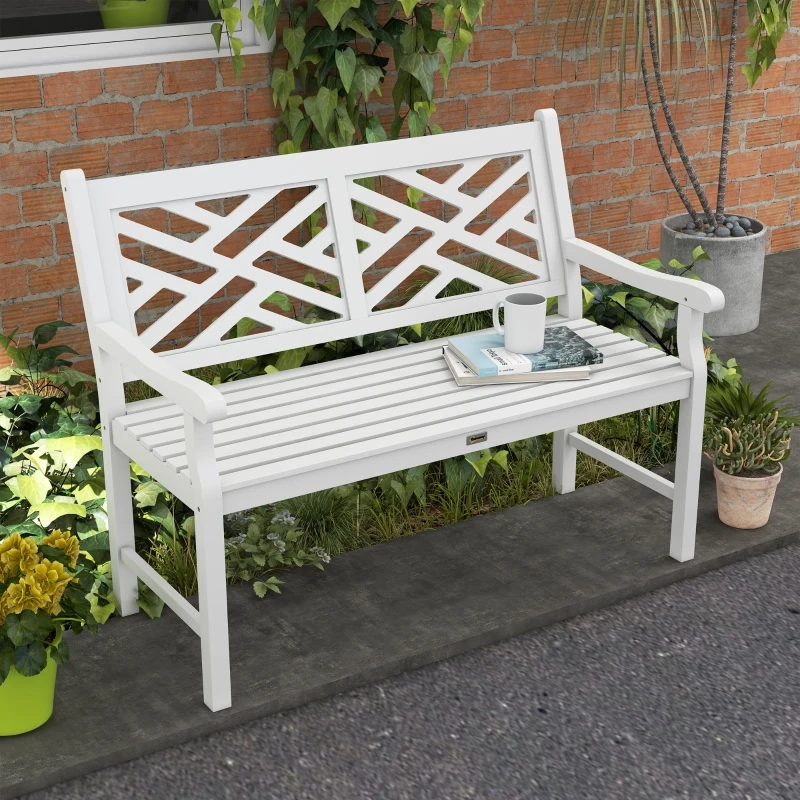 Un banc de jardin en bois lamellé blanc entouré de plantes et placé à côté d'un mur en brique.