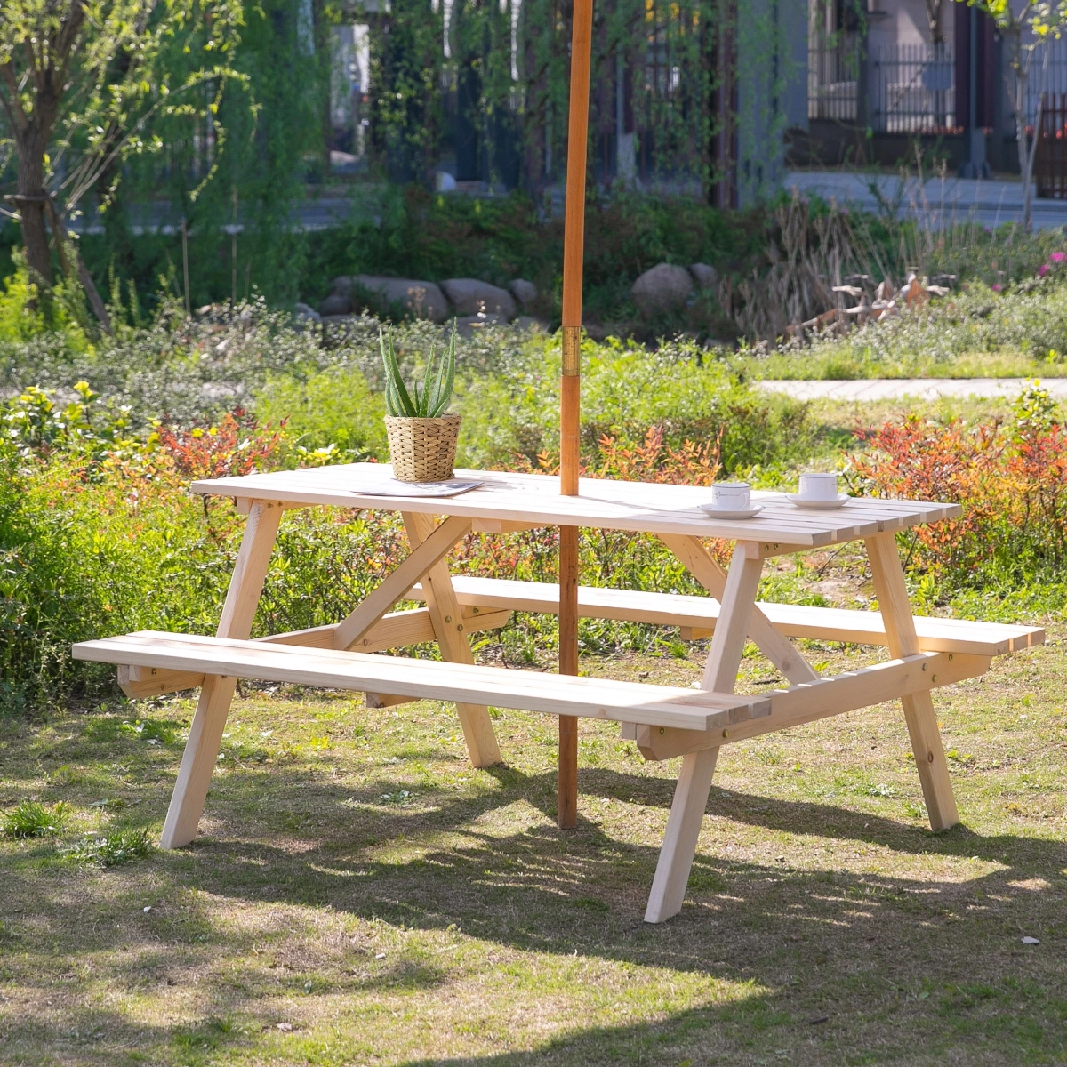 Table de pique-nique en bois fini posée dans un jardin vert extérieur, prête à être utilisée.