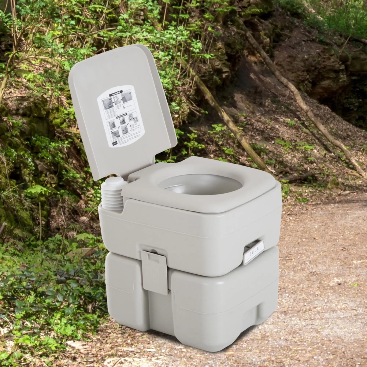 WC de voyage portable installé dans une zone de camping boisée avec des arbres.