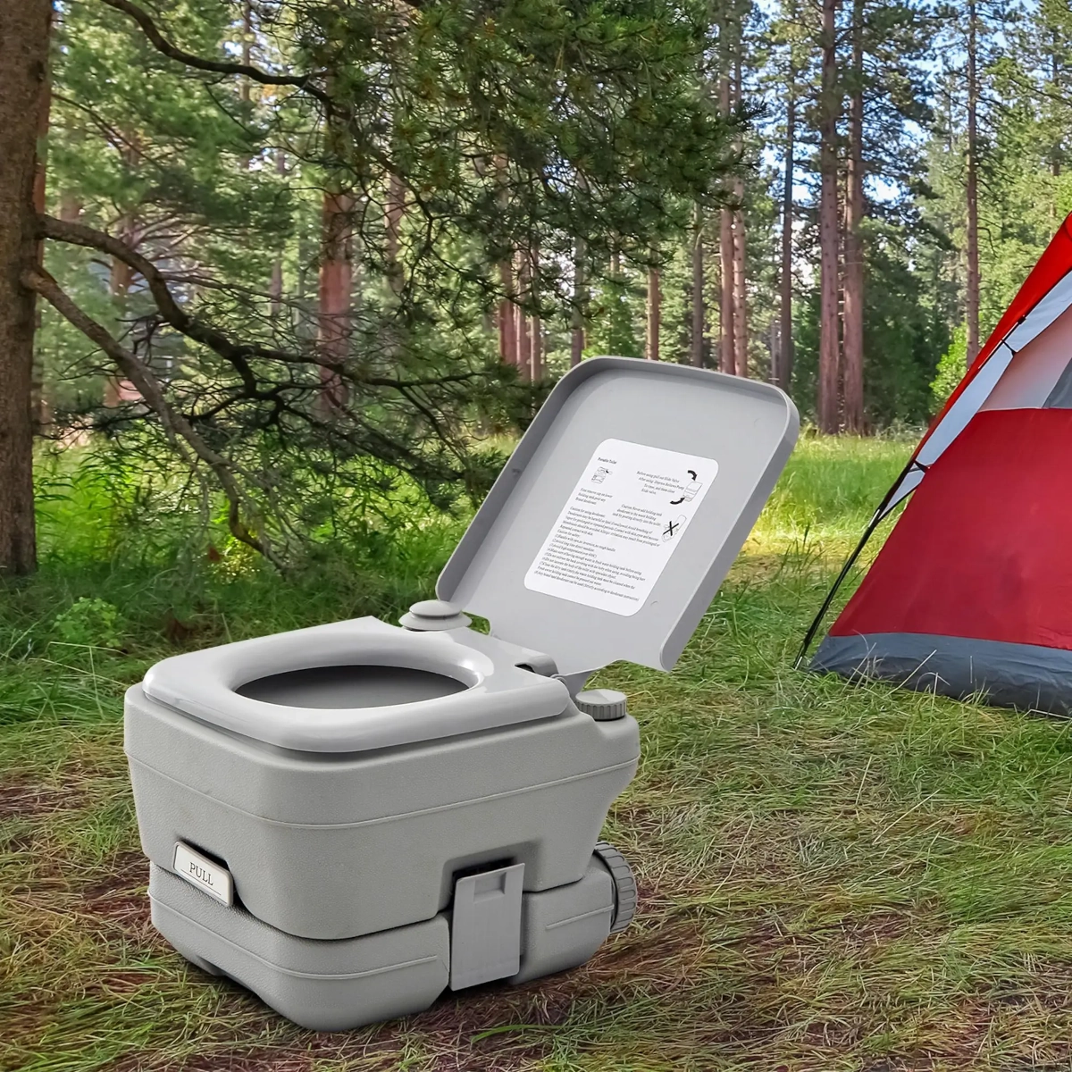WC de voyage portable compact à côté d'une tente de camping dans la nature.