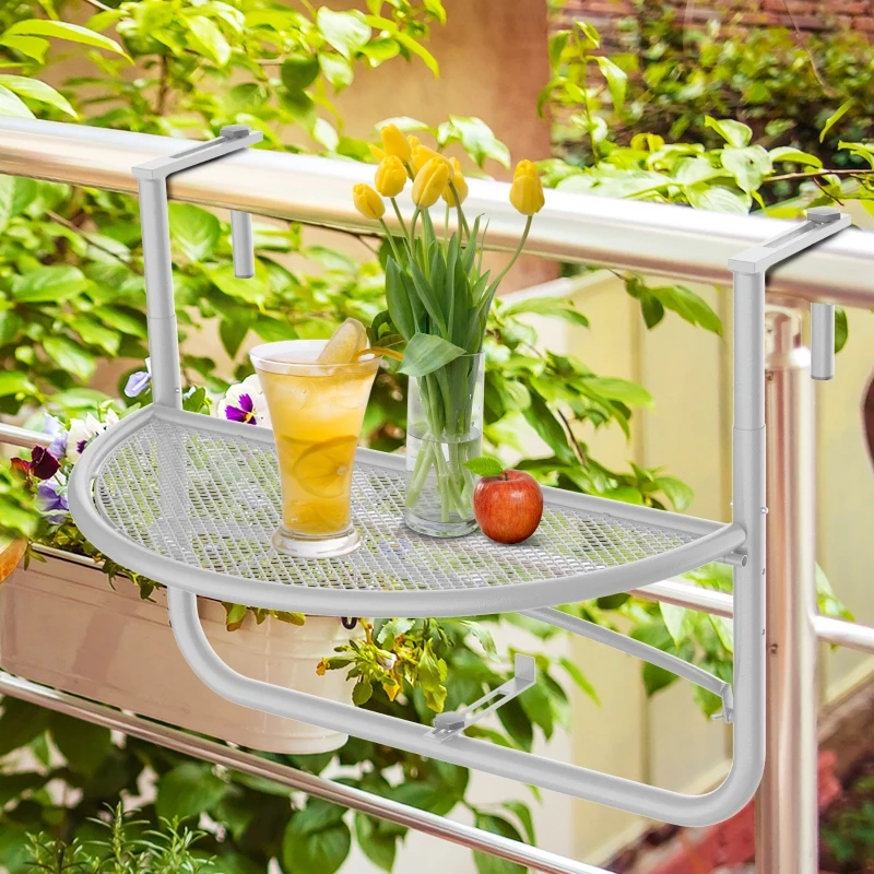 Table de balcon demi-ronde en maille avec des tulipes jaunes, du limonade et une pomme parmi des plantes de jardin vertes.