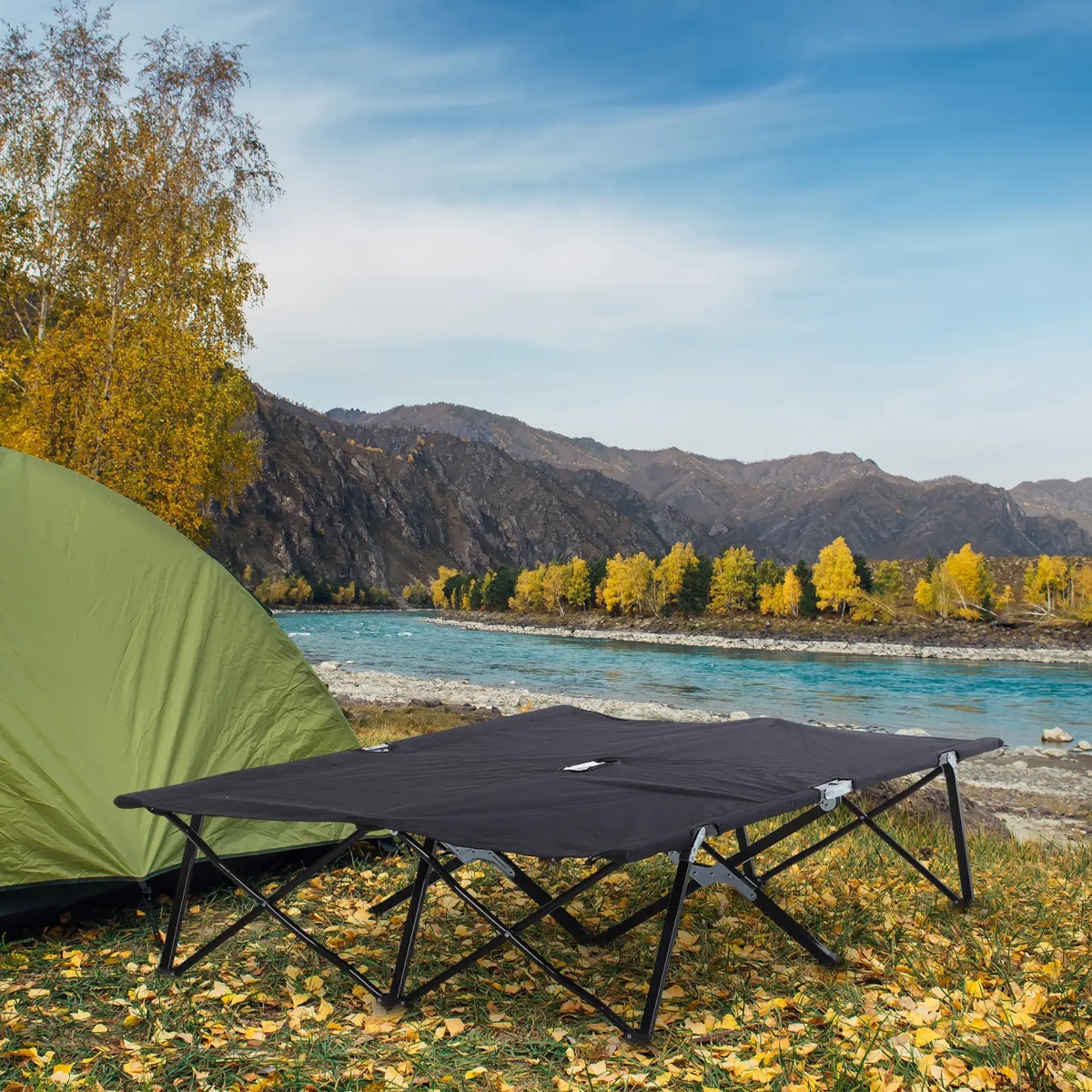 Grand lit de camping pour deux personnes avec support double cadre installé sur une surface plane près d'une tente.