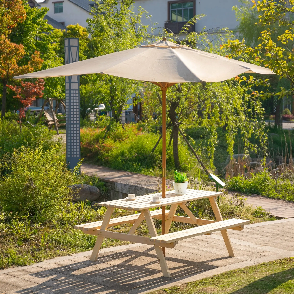 Table de pique-nique avec un grand parasol fournissant de l'ombre dans une zone ensoleillée du jardin.
