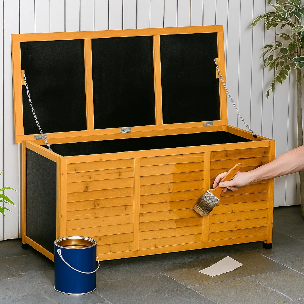Main appliquant du vernis à une boîte de rangement en bois extérieure pour la protéger de l'humidité et de la pourriture.