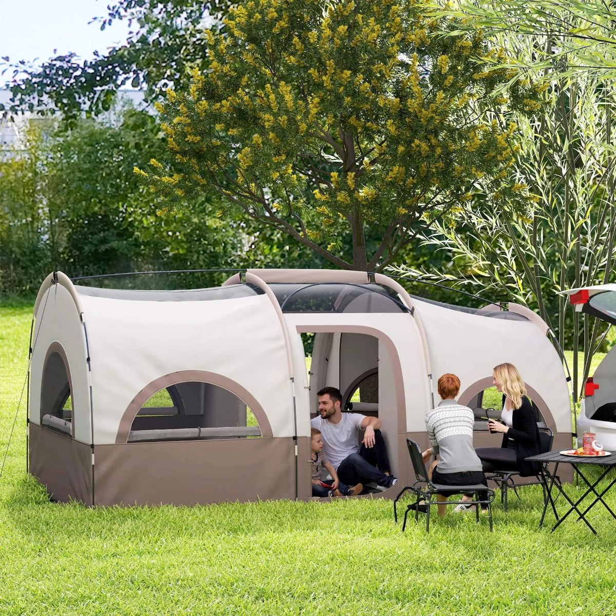 Tente spacieuse de style cabane dans une zone boisée, avec des chaises et une table installées à l’extérieur.