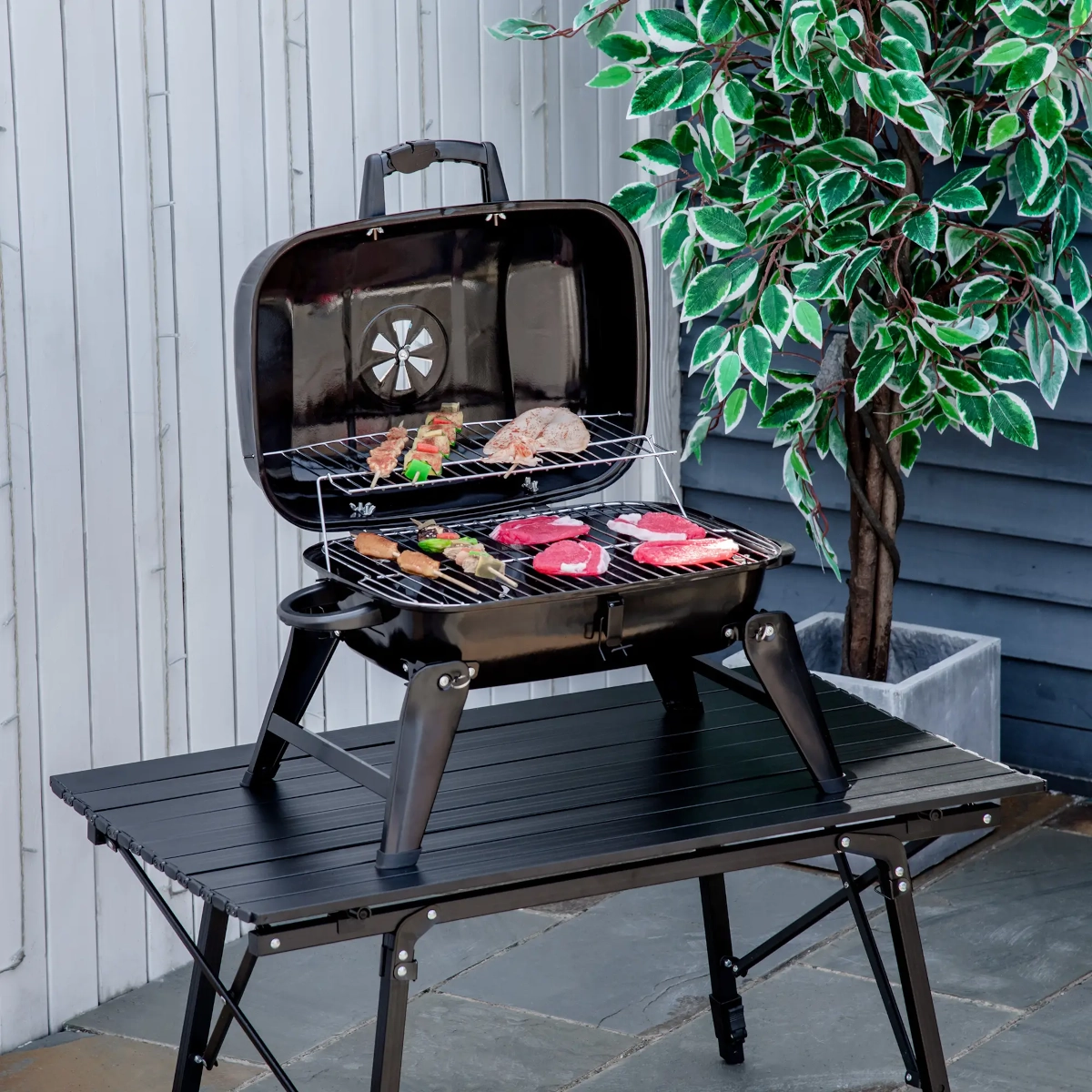 Barbecue portable de table au charbon avec viande et brochettes, parfait pour le camping et les barbecues en arrière-cour.