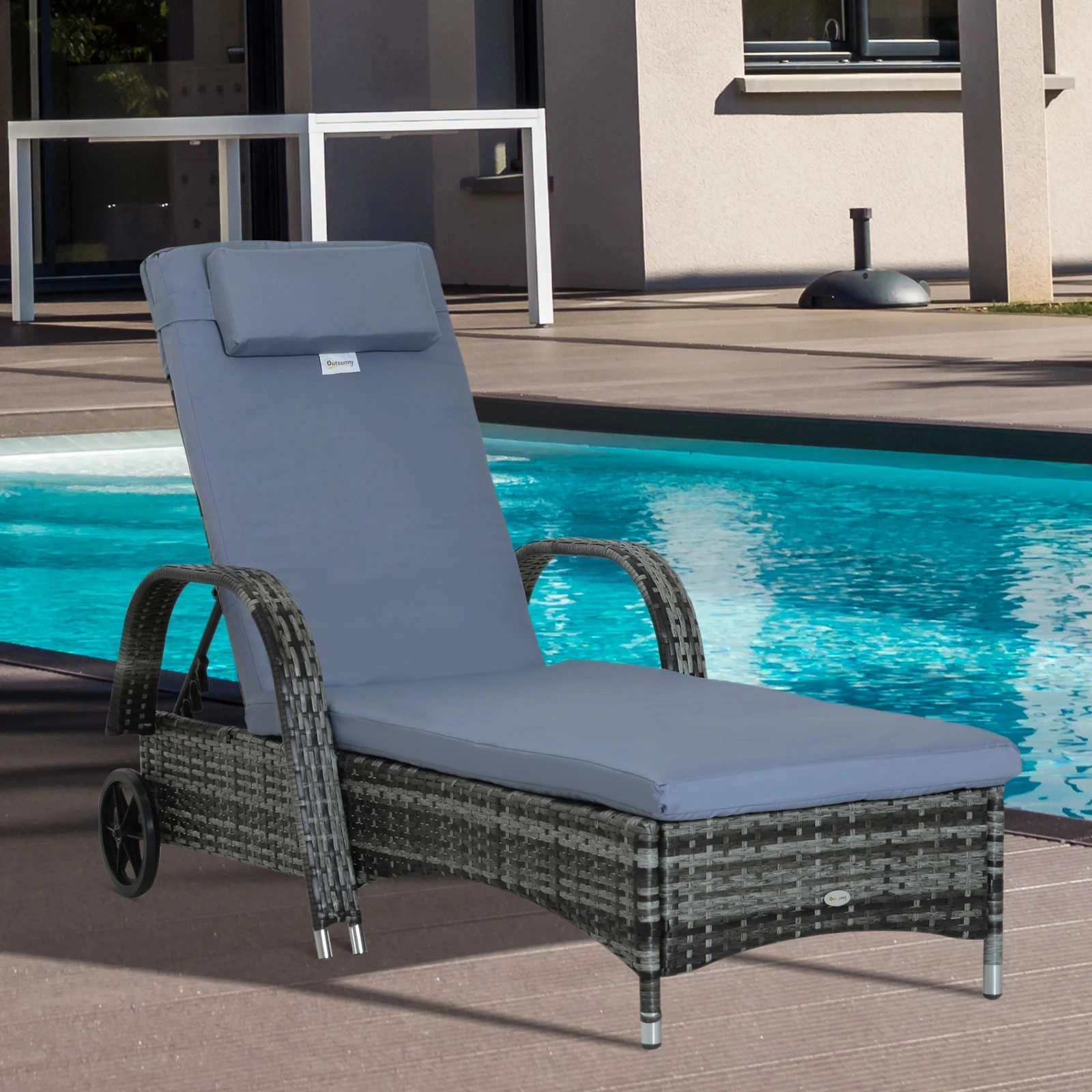 Chaise longue en rotin avec roulettes et coussin bleu placée sur une terrasse en bois à côté d'une piscine.