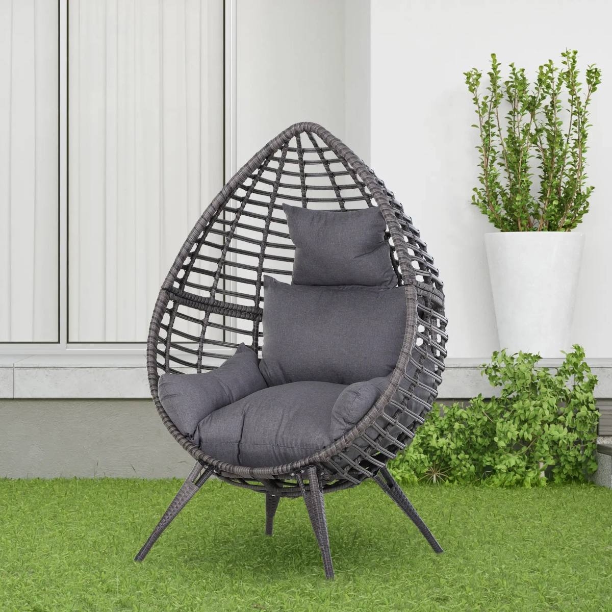 Fauteuil œuf extérieur confortable en rotin avec coussin, parfait pour se détendre dans un jardin.